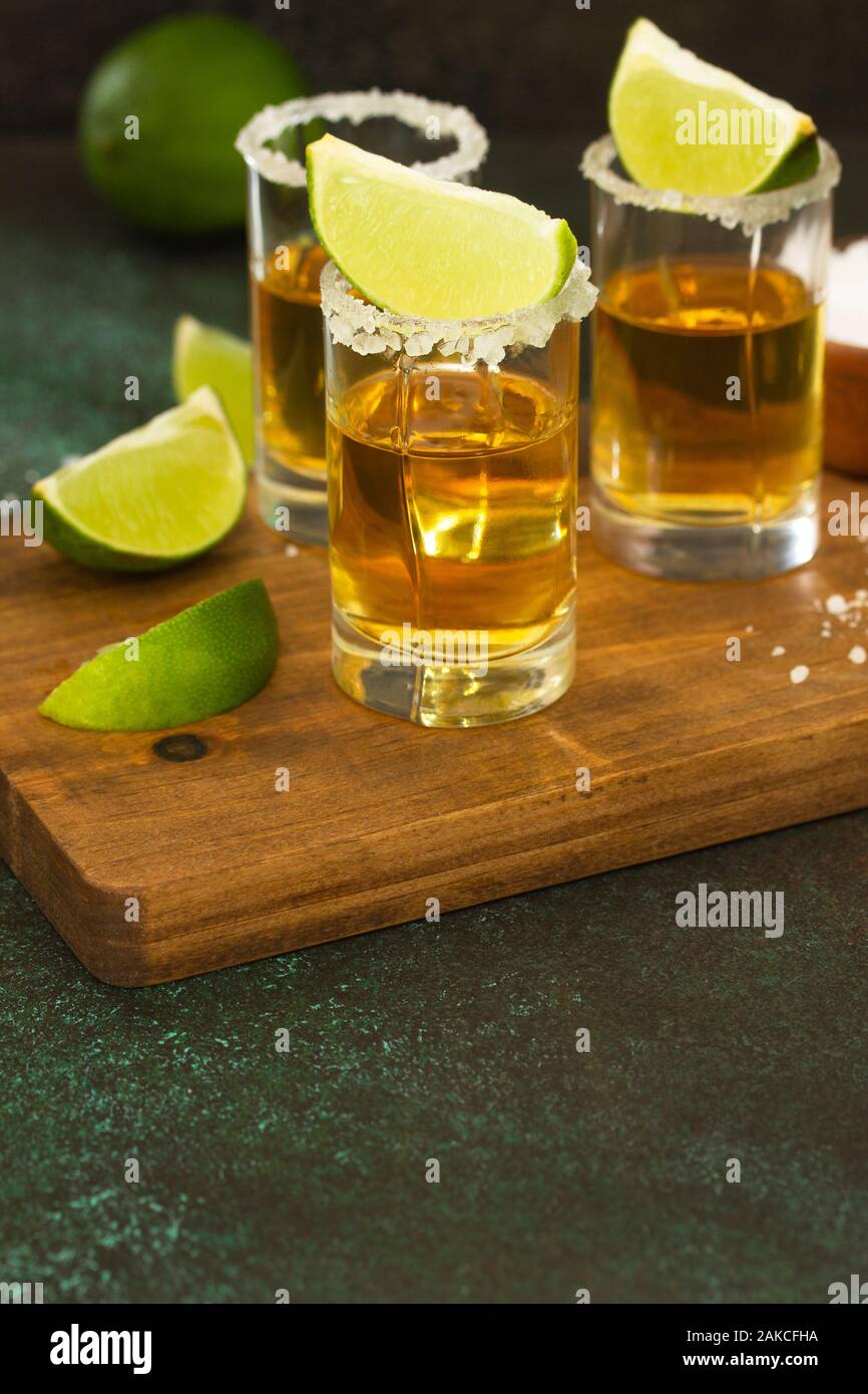 Mexican Gold Tequila shot con calce e sale sulla pietra scuro dello sfondo. Foto Stock