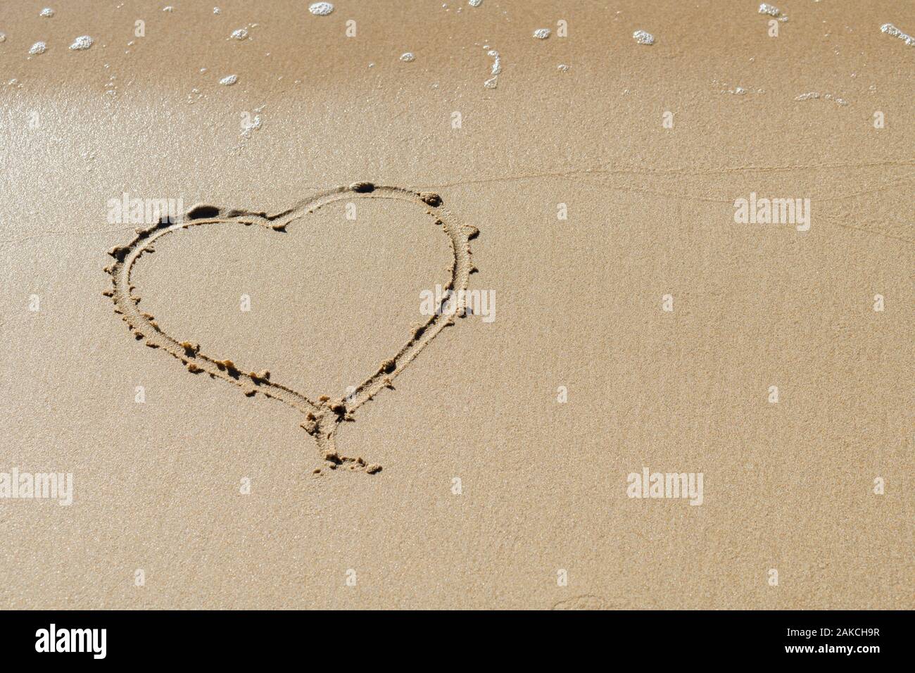 Forma di cuore disegnato nella sabbia in spiaggia Foto Stock