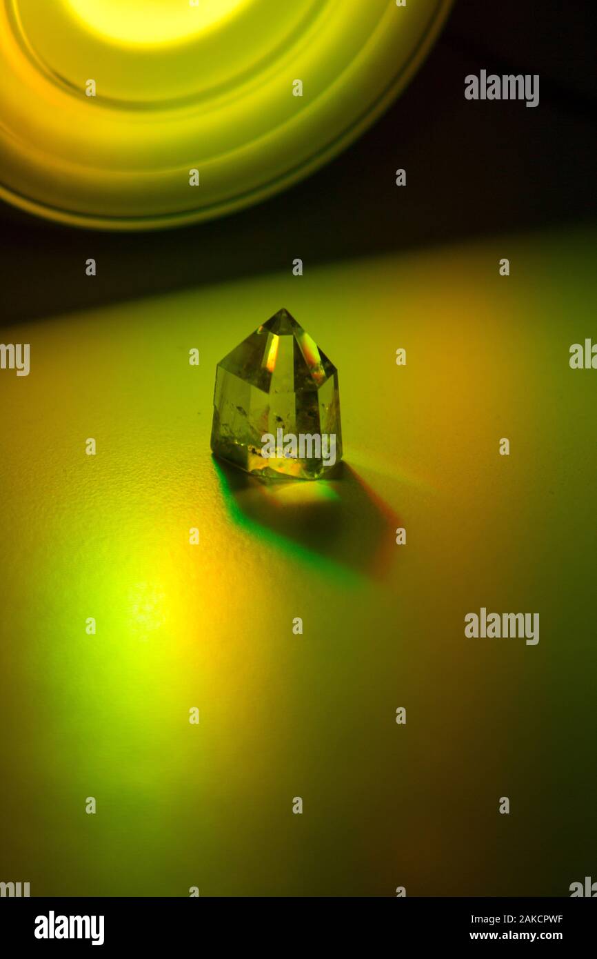 Chiudere l'immagine fissa di un giallo citrino crystal illuminato con colorati riflettori sul terreno neutrale. Foto Stock