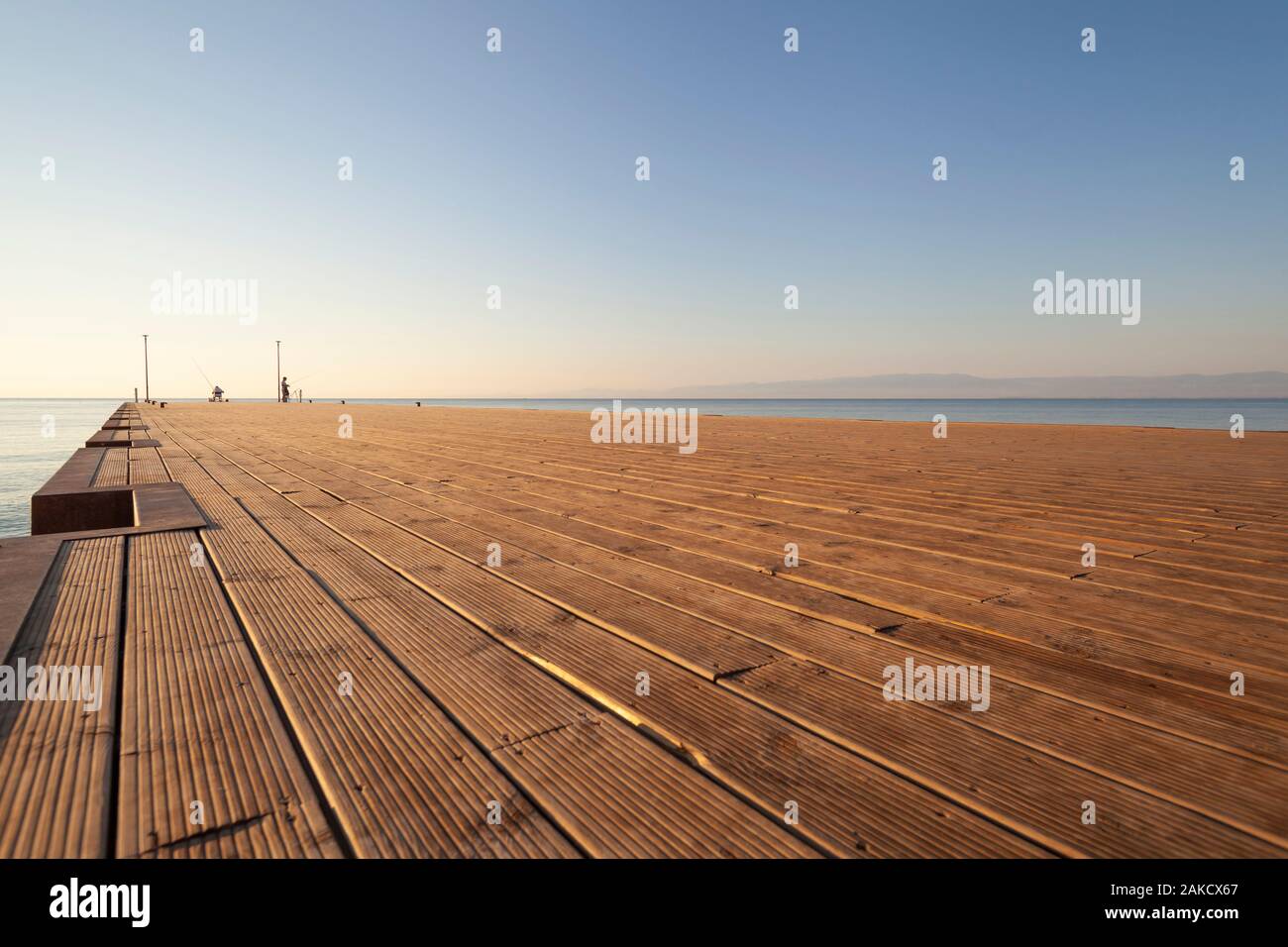 Il Molo sul Mare nelle prime ore del mattino con persone silhouette (terra vista obliqua all'orizzonte) Foto Stock