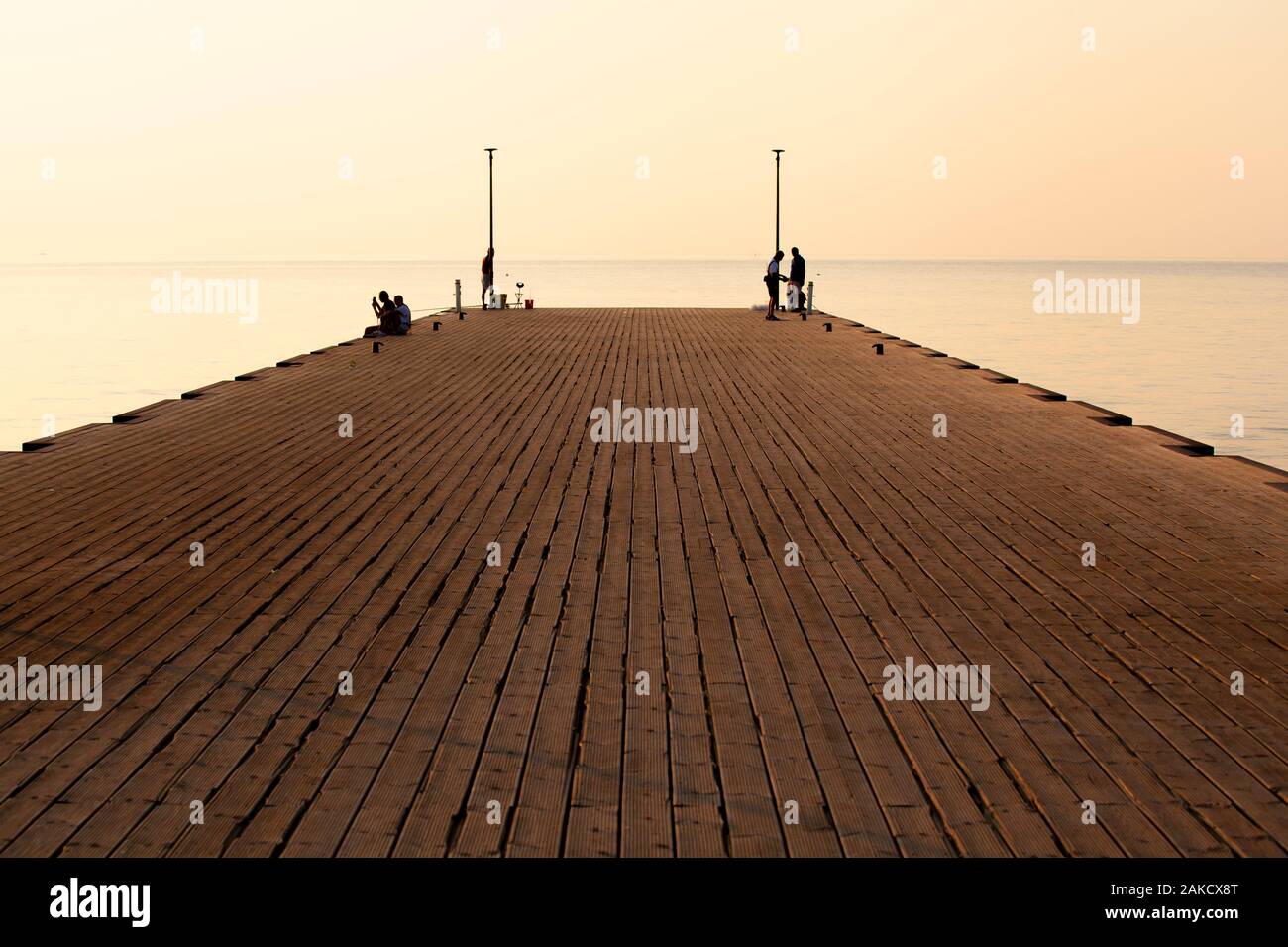 Il Molo sul Mare nelle prime ore del mattino con persone silhouette (vista in prospettiva) Foto Stock