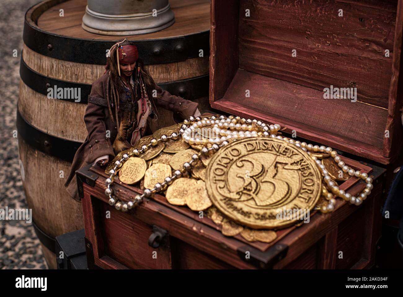 08.2018 Giappone.Tokyo Disney.Jack Sparrow monete.artificiale delle monete in oro e una decorazione su un barile di legno. Una tazza riempita con oro monete artificiale. Foto Stock