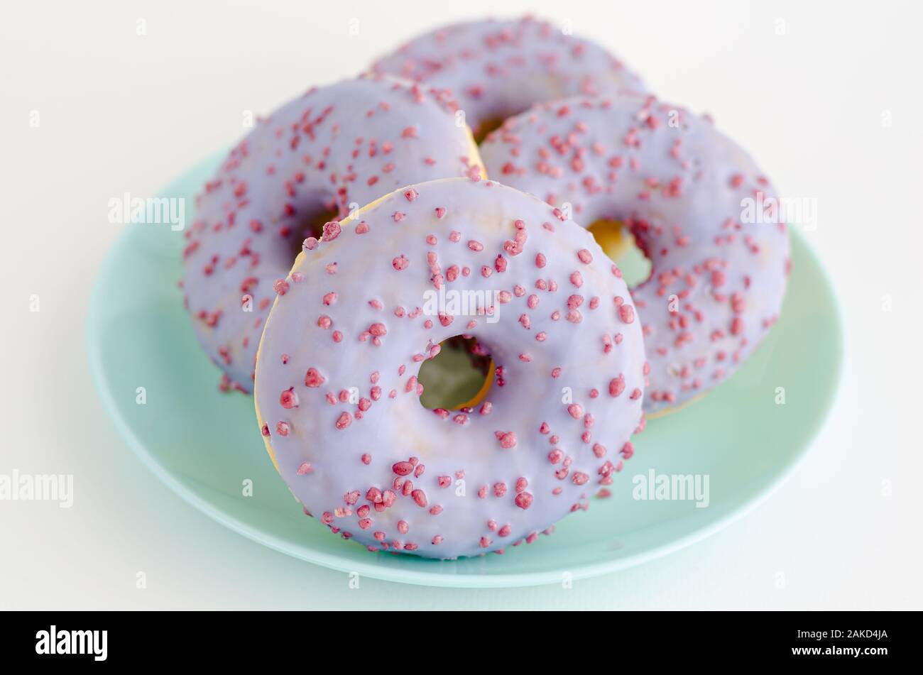 Viola sapore di frutta ciambelle su una piastra su sfondo bianco. Close up Foto Stock