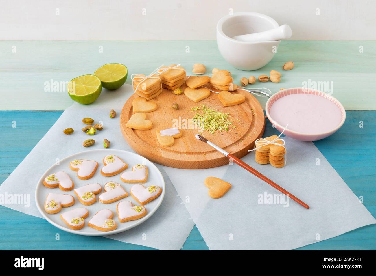 Preparare per il giorno di San Valentino. Iced piccante biscotti frollini nel cuore forme, abbellito con calce-lampone ghiaccio tritato e i pistacchi. La cottura wi Foto Stock