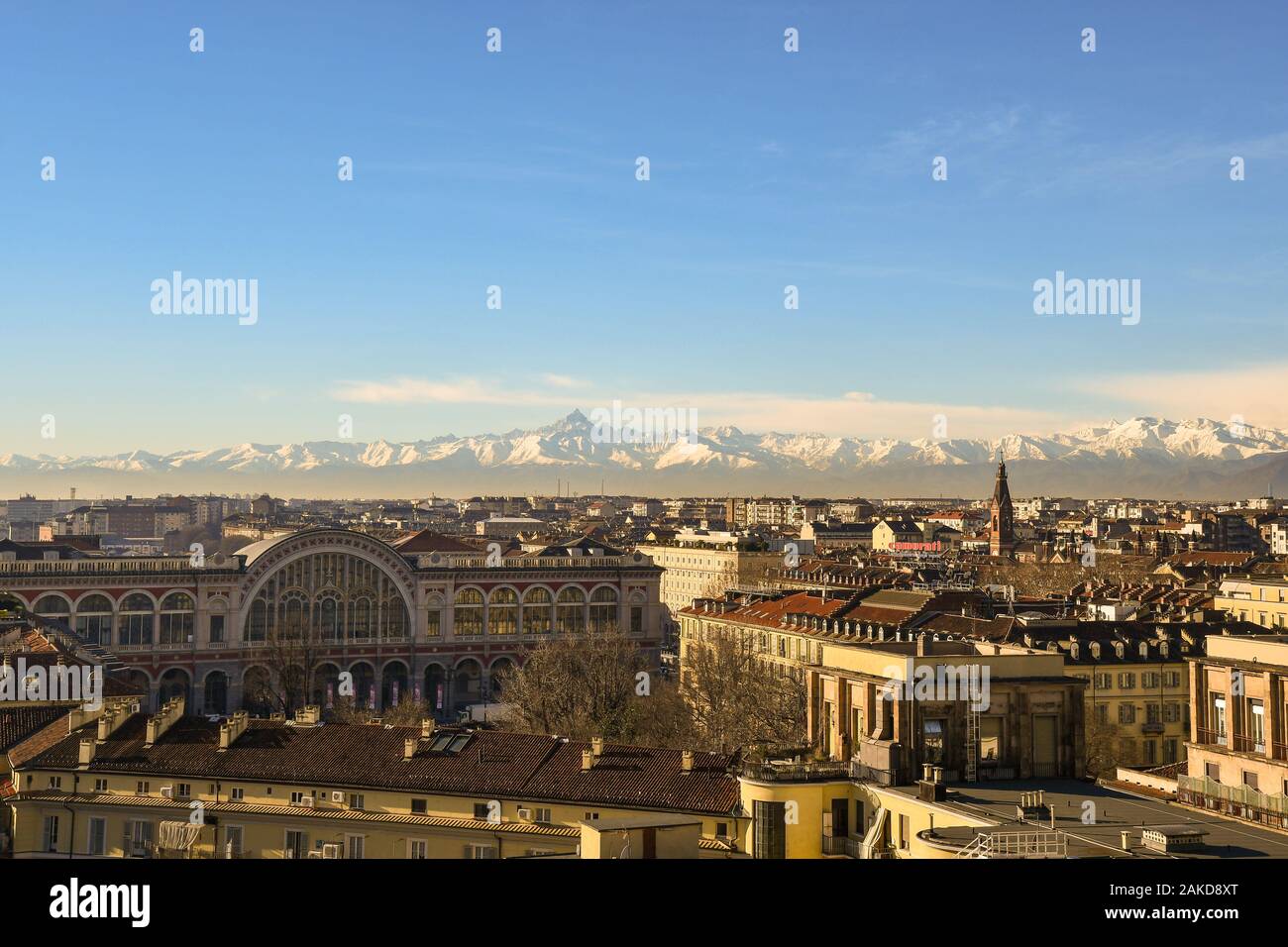 Vista sui tetti della città di Torino con la parte superiore della stazione ferroviaria di Porta Nuova e Alpi Cozie con il Monviso picco in una soleggiata giornata invernale, Piemonte, Italia Foto Stock