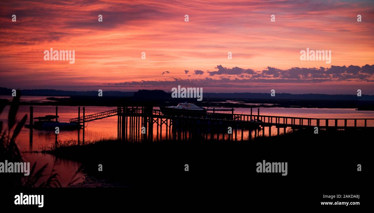 Cielo romantico su un molo e una barca al tramonto. Foto Stock