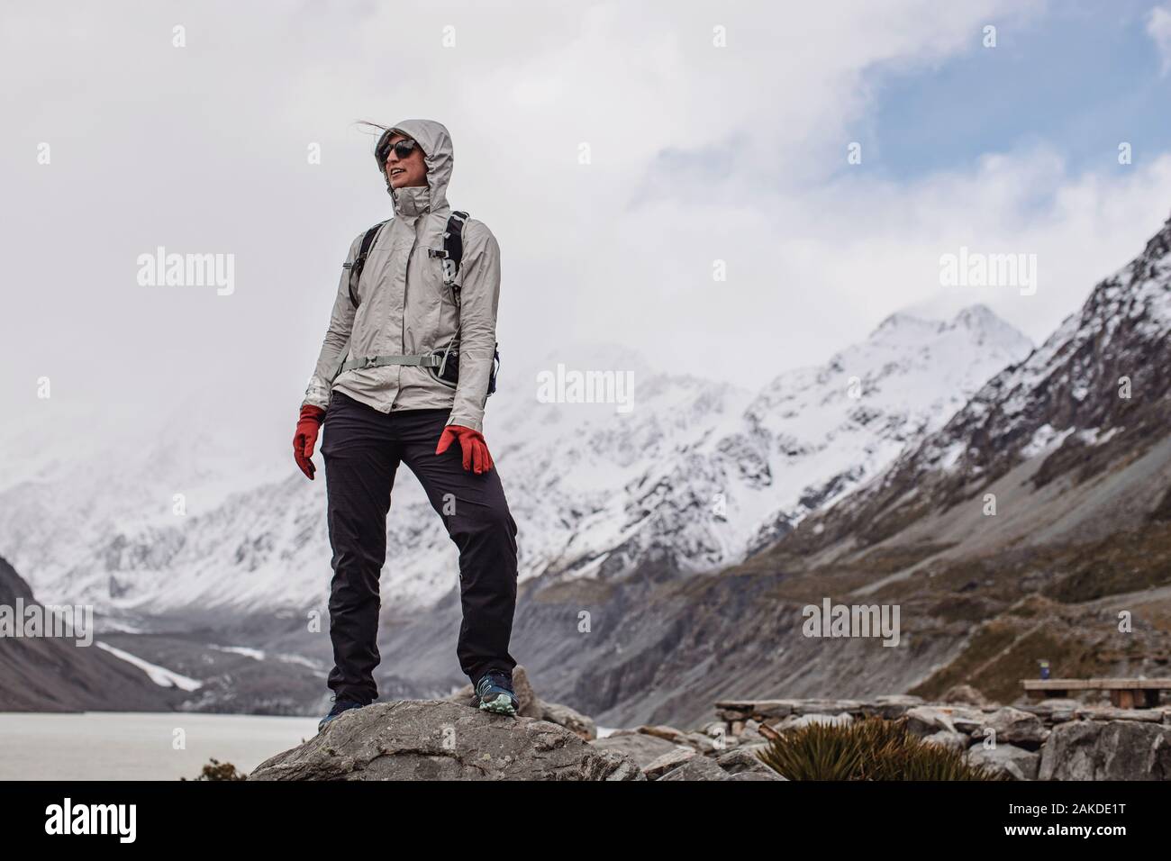 La donna fredda si erge sulla roccia mentre si fa un'escursione a Hooker Valley in Nuova Zelanda Foto Stock