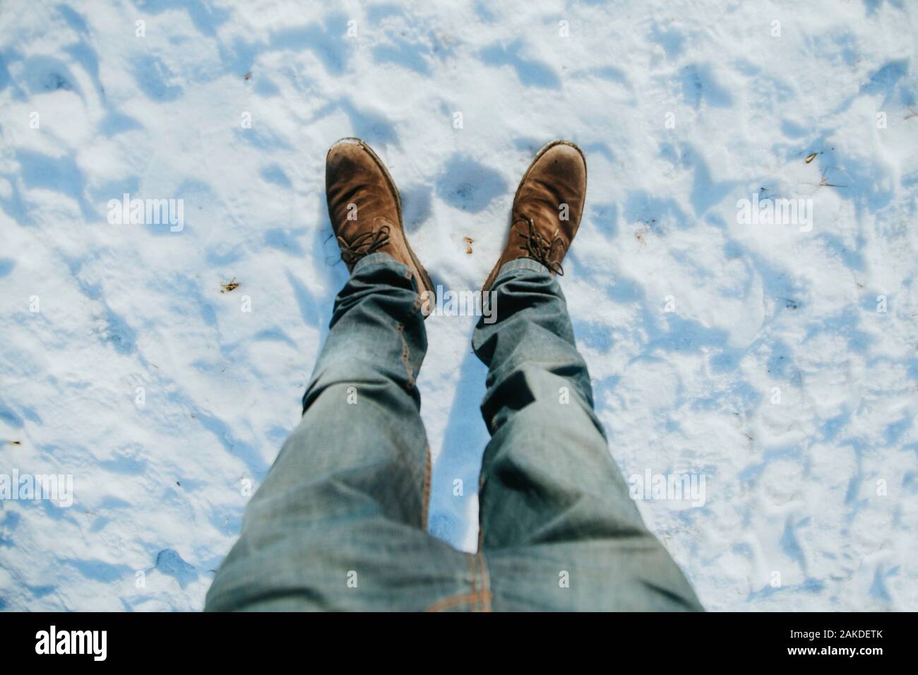 Primo piano delle gambe maschili nelle scarpe invernali in piedi sulla neve Foto Stock
