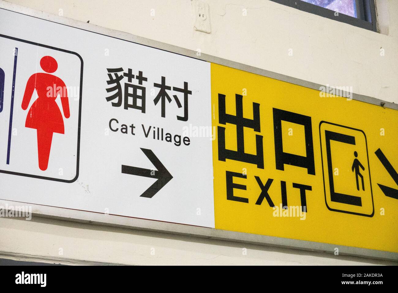 Un cartello bilingue in Mandarino e Inglese alla stazione ferroviaria di Houtong, che indica la direzione per il Villaggio Cat e l'uscita Foto Stock