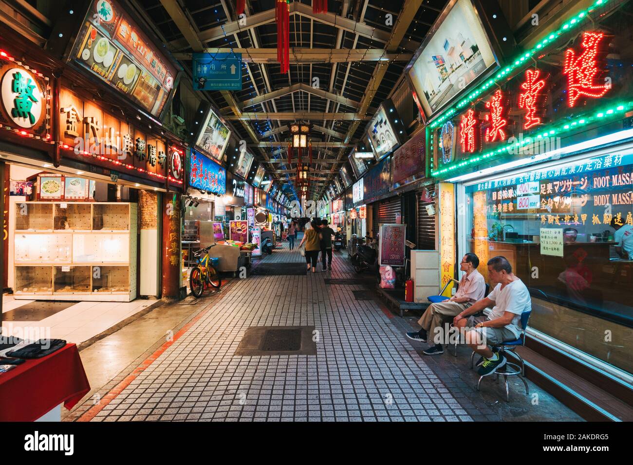 Due uomini si siedono in un vuoto Huaxi Street Night Market, all'orario di chiusura, a Taipei, Taiwan Foto Stock