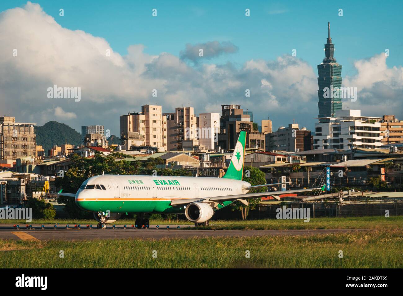 Un Airbus A321 EVA Air si allinea per il decollo in una serata di sole all'Aeroporto Songshan di Taipei. Il grattacielo Taipei 101 è visibile dietro Foto Stock