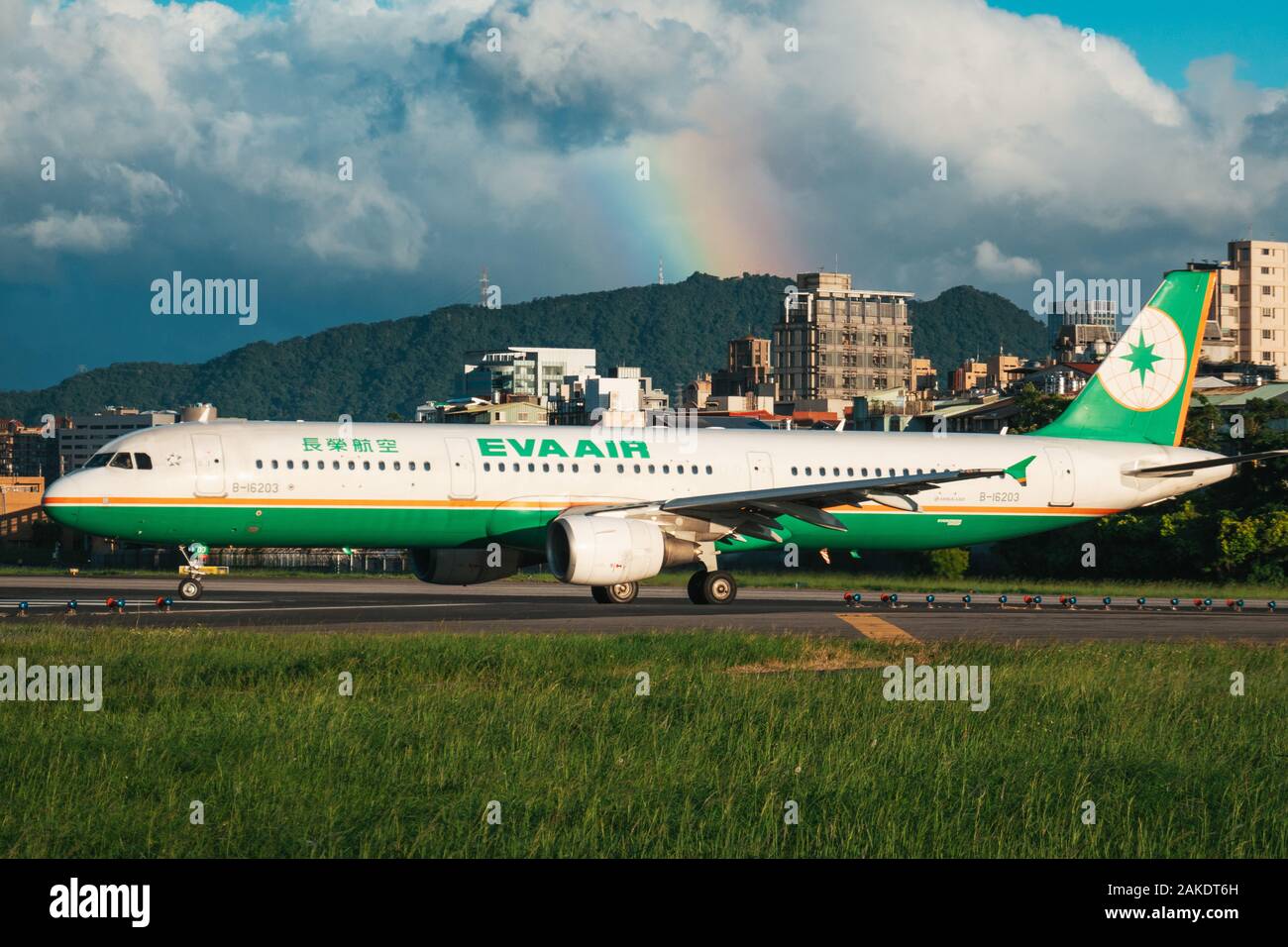 Un Airbus A321 EVA Air si allinea per il decollo in una serata di sole all'Aeroporto Songshan di Taipei. Un arcobaleno è visibile dietro Foto Stock