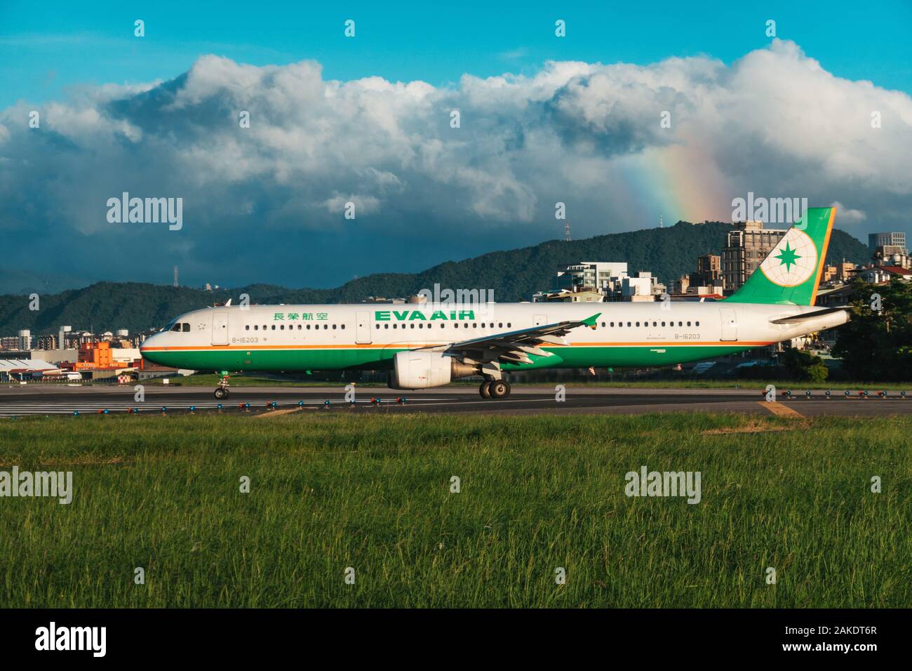 Un Airbus A321 EVA Air si allinea per il decollo in una serata di sole all'Aeroporto Songshan di Taipei. Un arcobaleno è visibile dietro Foto Stock