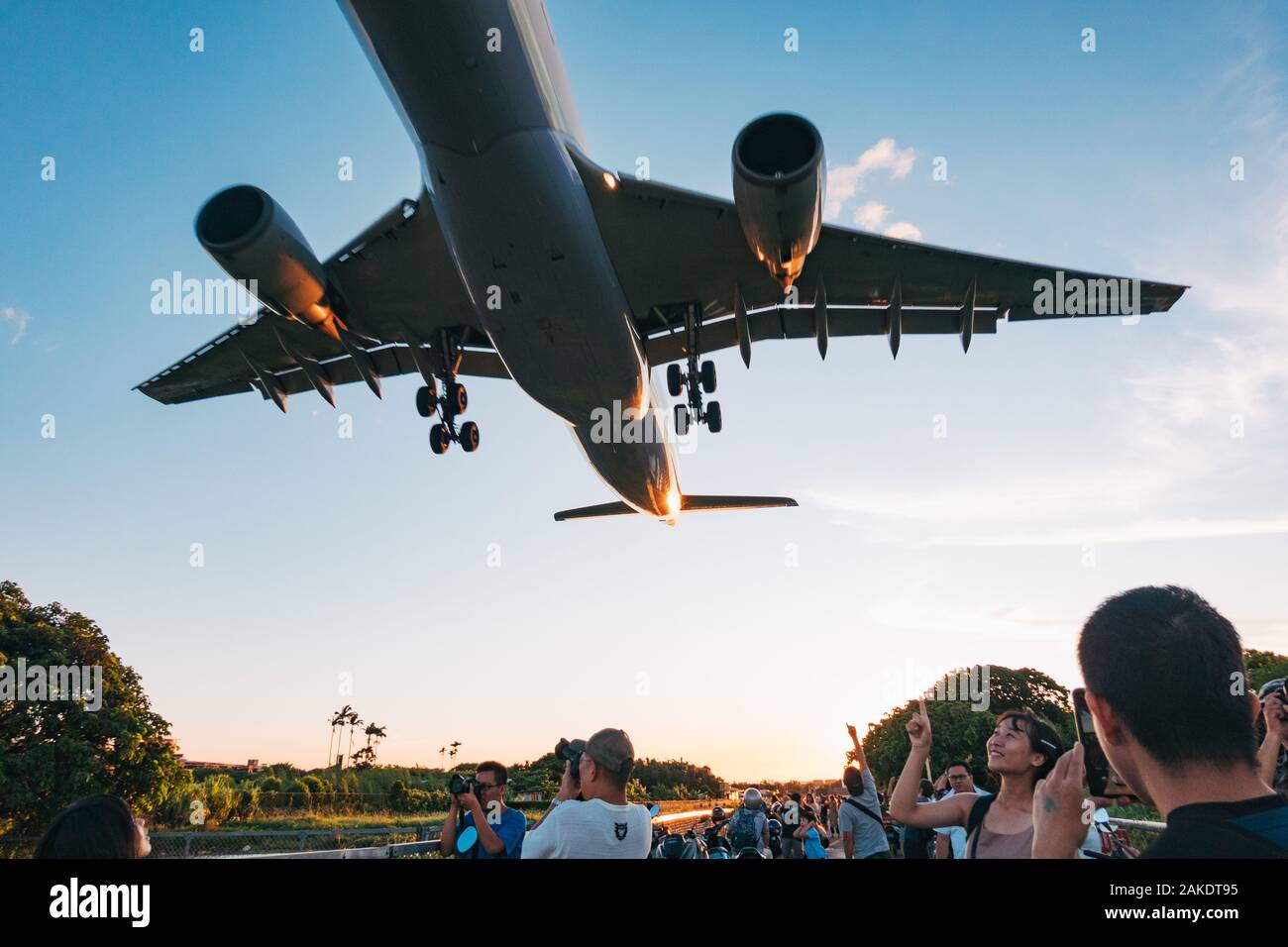 Onloookers fuoco fuori le foto come un Airbus A330 urla sopra, appena fuori della recinzione perimetrale dell'aeroporto di Songshan, Taipei Foto Stock