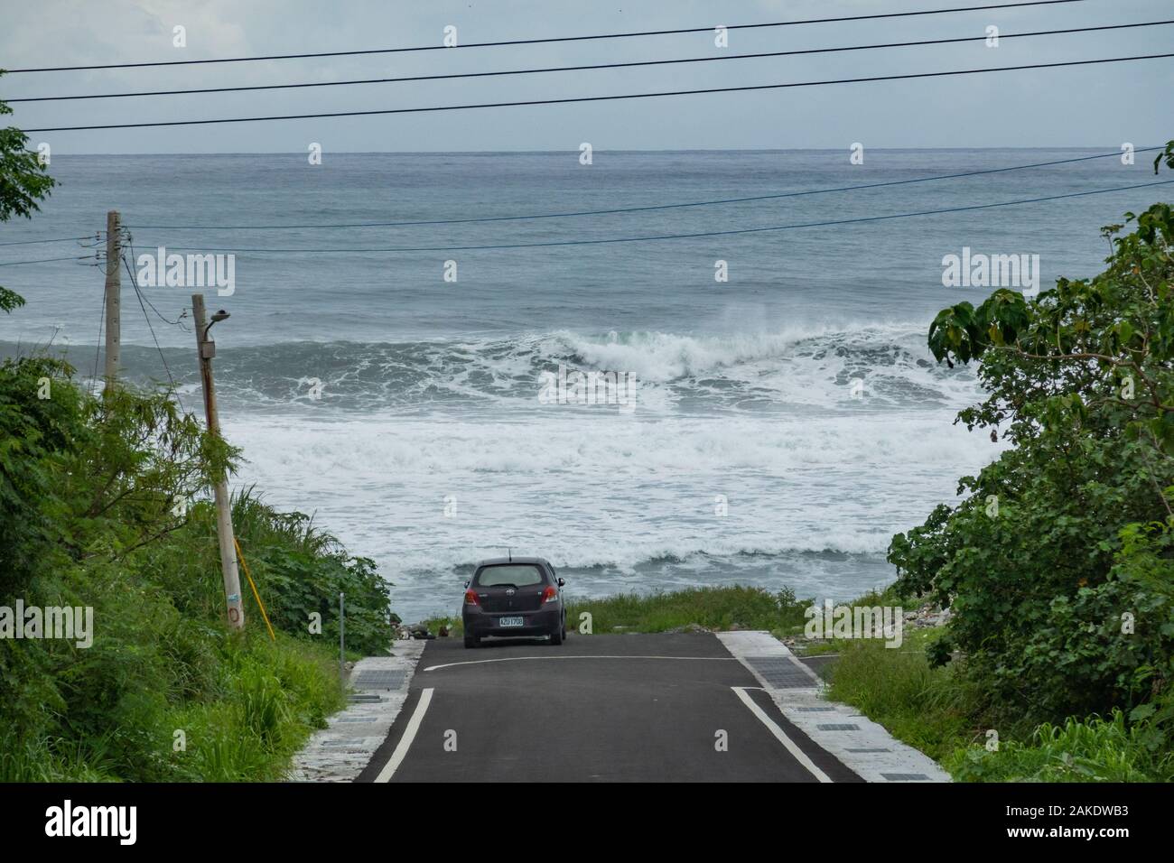 Grandi onde si infrangono nella parte anteriore di una macchina parcheggiata vicino alla spiaggia di Dulan, nel sud di Taiwan, dopo un ciclone passò da Foto Stock