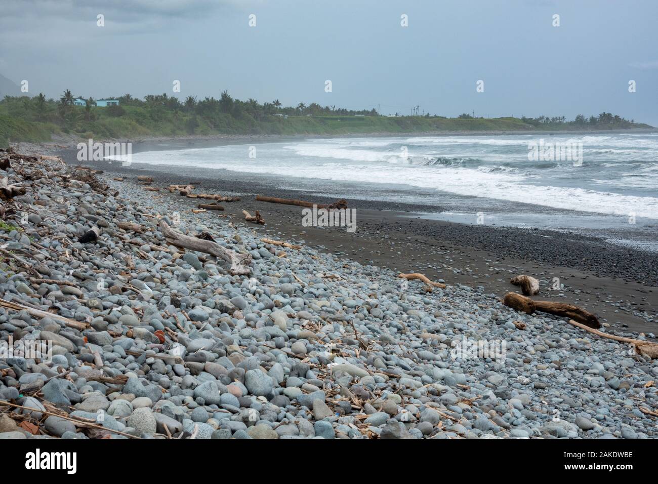 Forti onde si infrangono sulla spiaggia rocciosa di Dulan Beach, nel sud di Taiwan, dopo un ciclone passò da, lavaggio a terra di grandi pezzi di driftwood Foto Stock