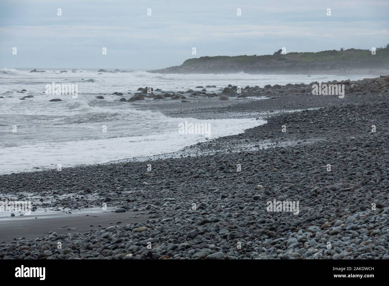 Forti onde si infrangono sulla spiaggia rocciosa di Dulan Beach, nel sud di Taiwan, dopo un ciclone passò da, lavaggio a terra di grandi pezzi di driftwood Foto Stock