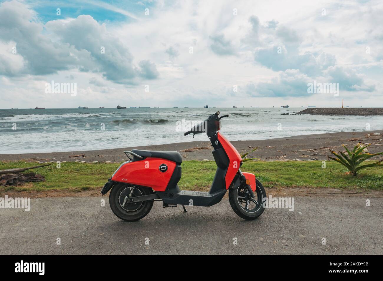 Un rosso Super Soco CU scooter elettrico parcheggiato su un percorso in Qijin parco costiero, Qijin Isola, Kaohsiung, Taiwan Foto Stock