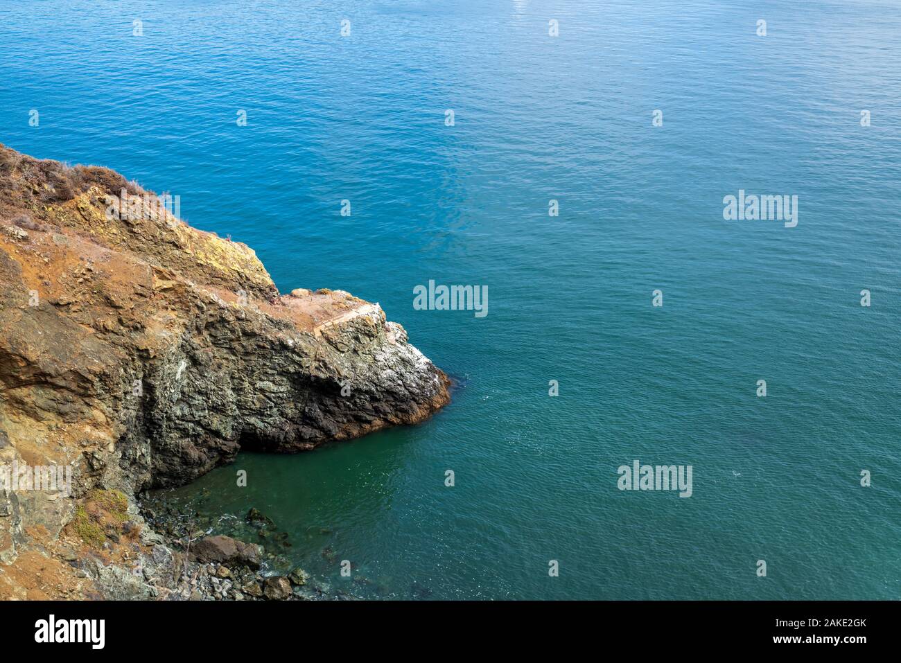 Scogliere sul mare che conduce al corpo di calme acque oceaniche sulla giornata di sole Foto Stock