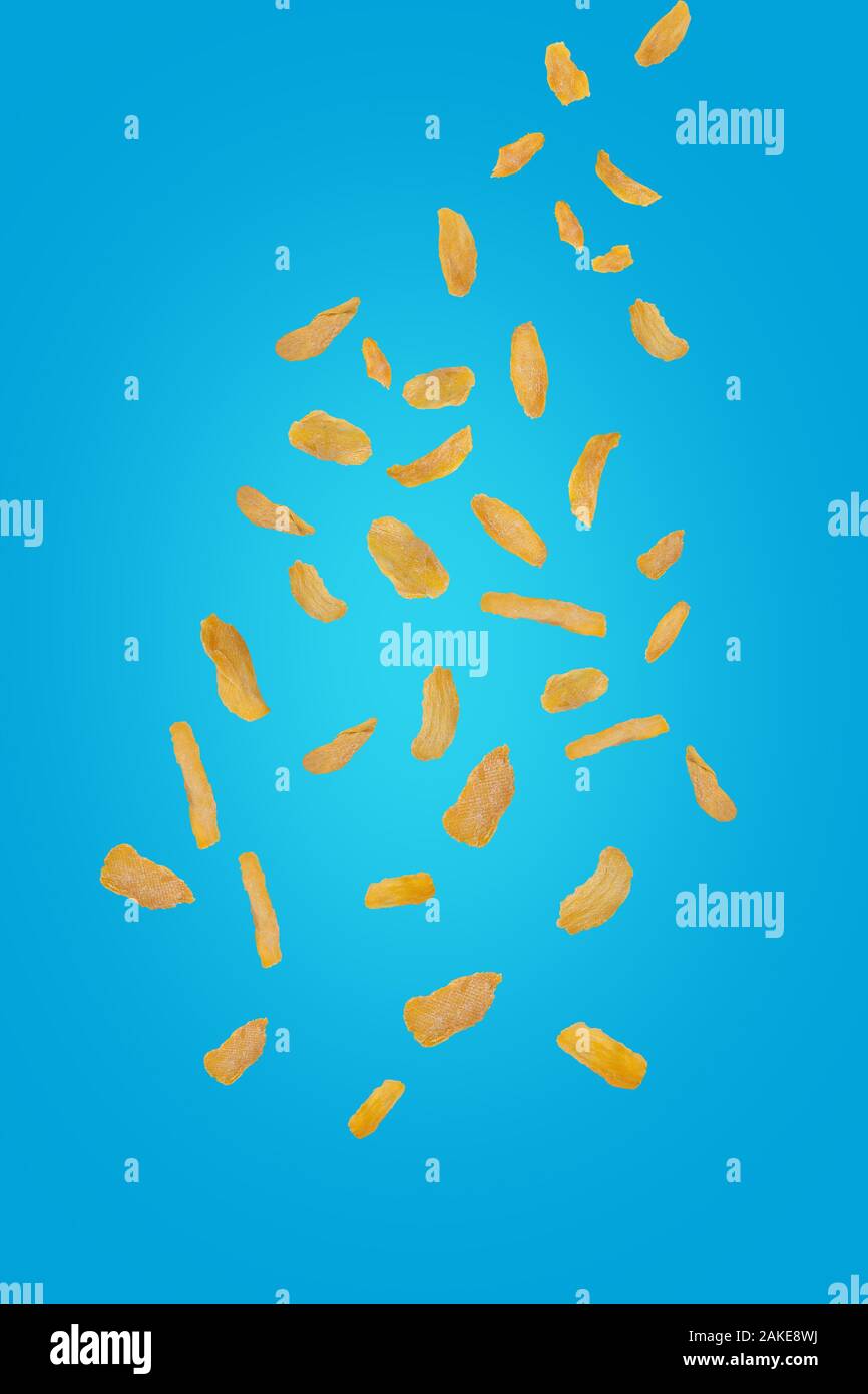 Flying mango chip su un sfondo turchese. Battenti di frutta. Verticalmente. Mango i trucioli cadono verso il basso. Foto Stock
