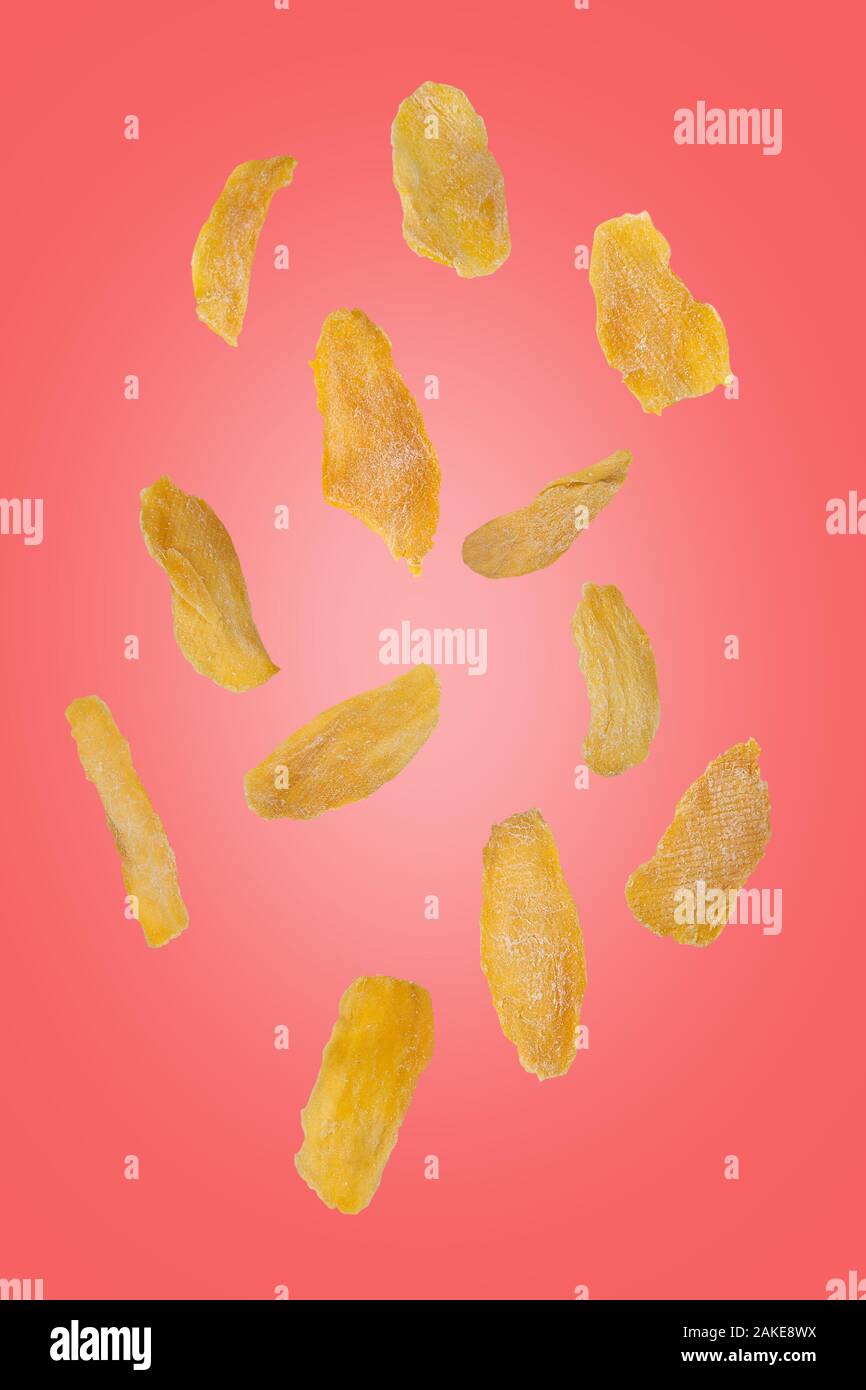 Flying mango chip su un sfondo rosa. Battenti di frutta. Verticalmente. Foto Stock