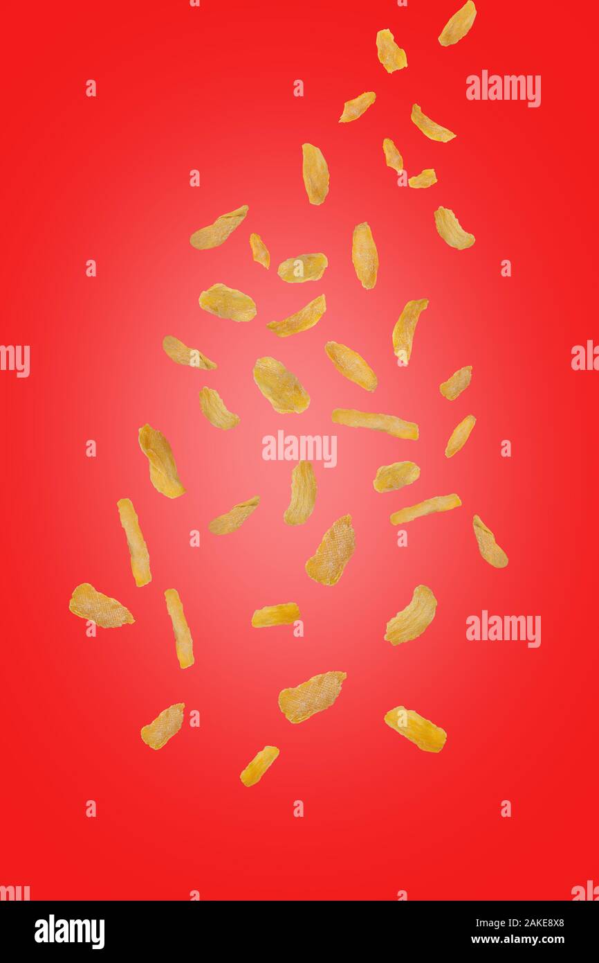 Flying mango chip su uno sfondo di colore rosso. Battenti di frutta. Verticalmente. Mango i trucioli cadono verso il basso. Foto Stock