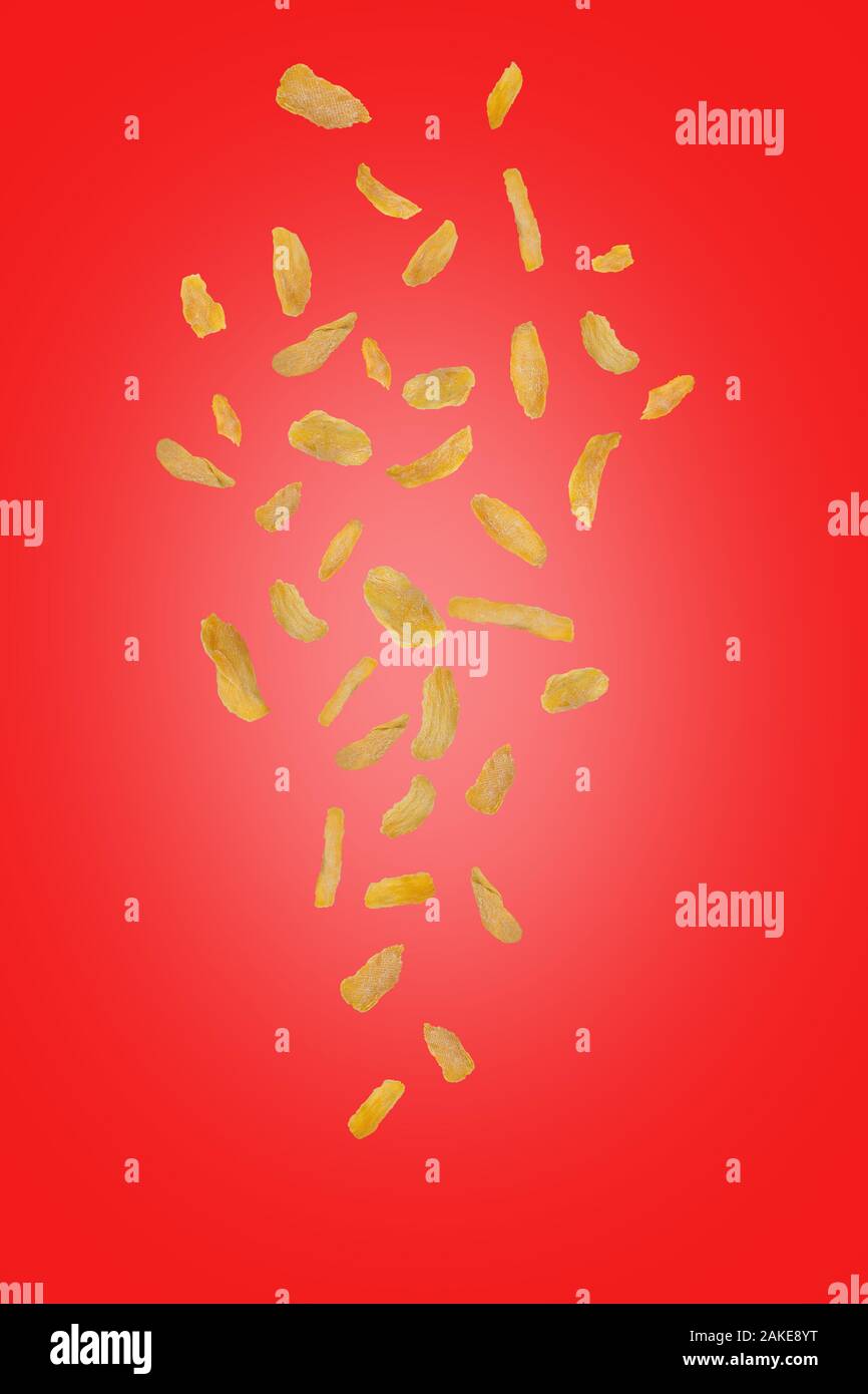Flying mango chip su uno sfondo di colore rosso. Battenti di frutta. Verticalmente. Chip di mango crumblel verso il basso. Foto Stock