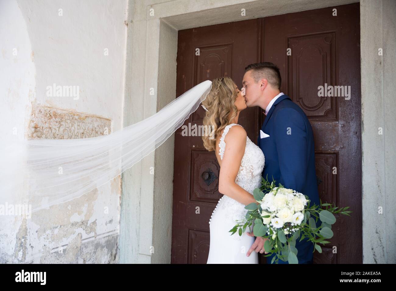 Il bacio. Sposa e lo sposo baci teneramente nella parte anteriore del portale della chiesa. Foto Stock