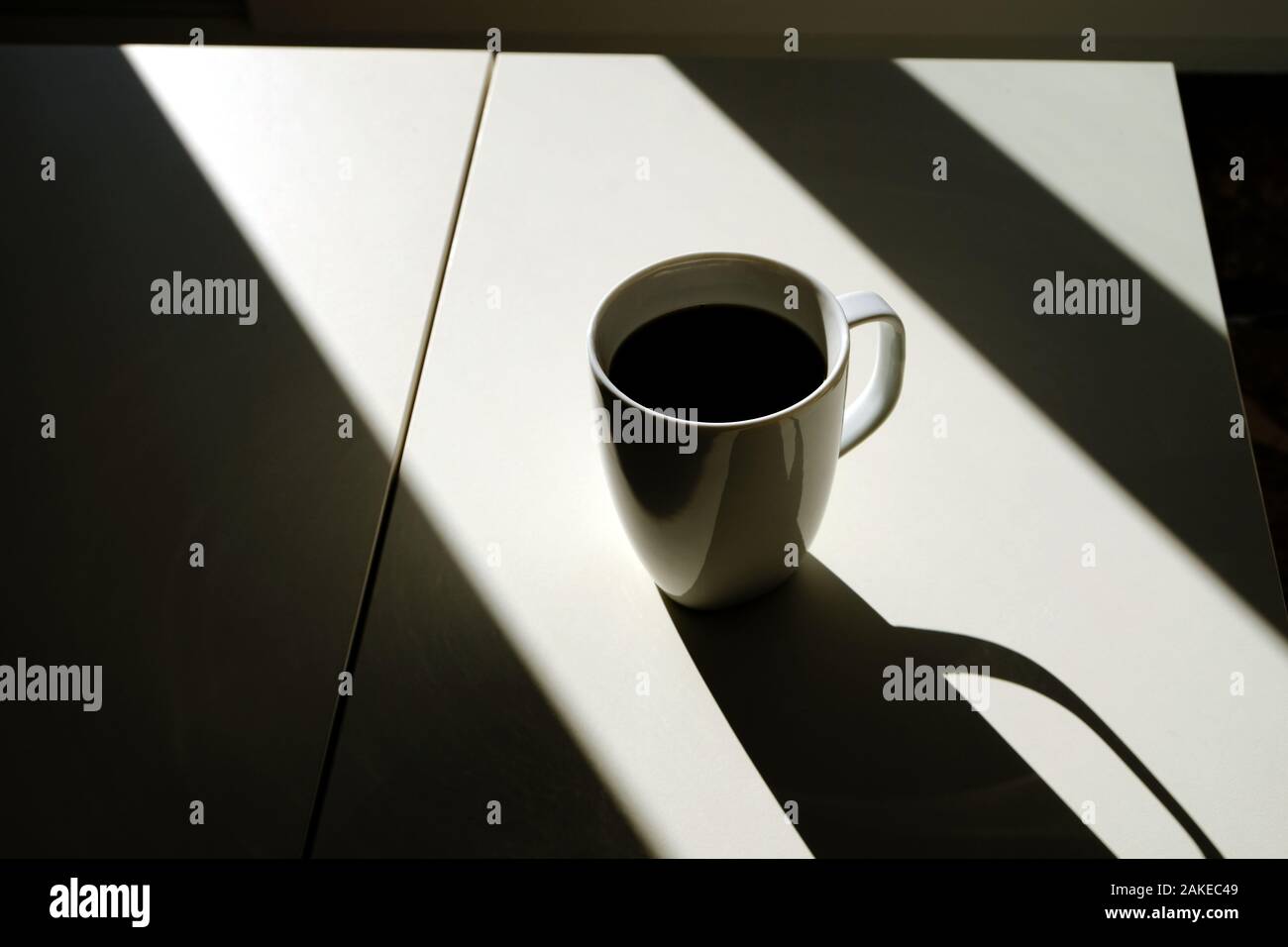una tazza di caffè in luce e ombra sul tavolo bianco Foto Stock