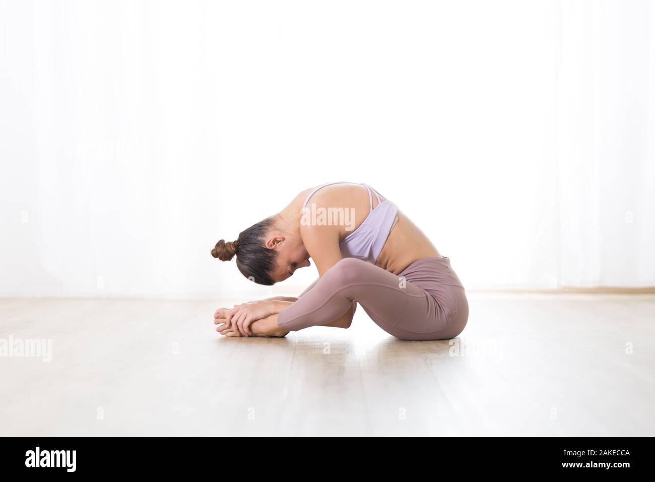 Ritratto di splendida sportiva attiva giovane donna a praticare yoga in studio. Bella ragazza pratica Dandayamana Bibhaktapada Paschimotthanasana Foto Stock