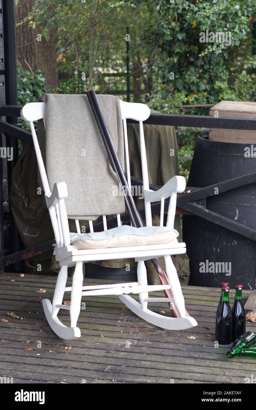 Vecchio di legno sedia a dondolo e tiro pistola con birra su una veranda in legno nel selvaggio west Foto Stock