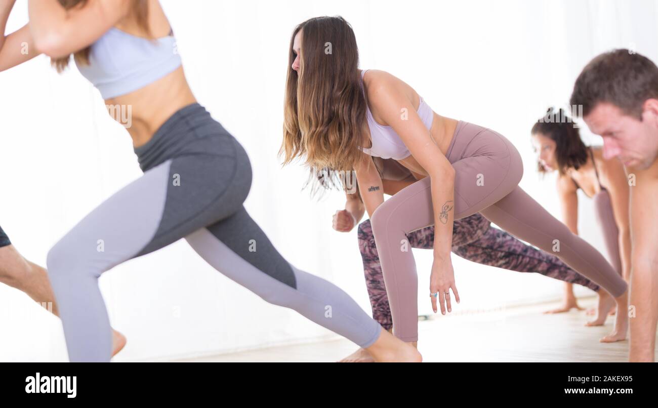 Un gruppo di giovani sportivi donne attraenti in studio di yoga, la pratica dello yoga lezione con istruttore, in piedi, stretching e rilassante dopo allenamento Foto Stock