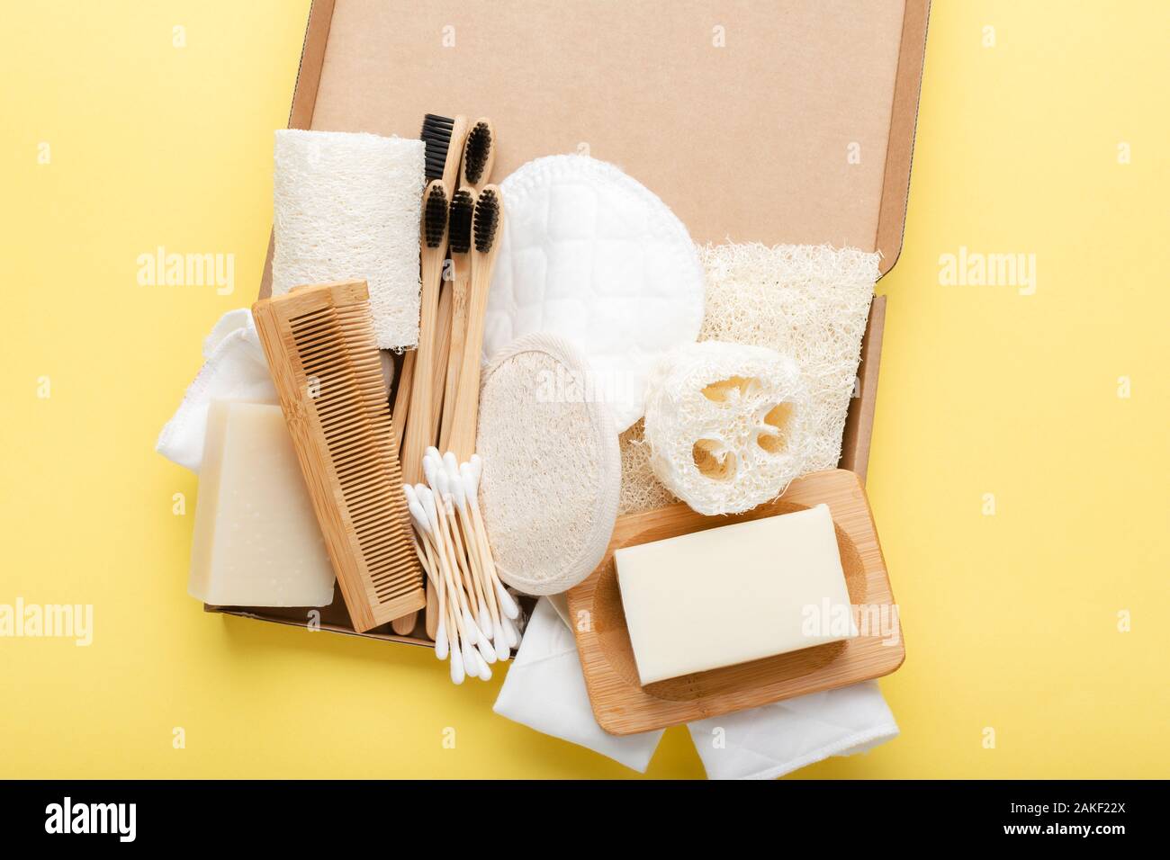 Rifiuti Zero con naturale self care accessori su giallo. Gli spazzolini da denti di bambù, sapone artigianale shampoo bar, batuffoli di cotone pastiglie, prodotti di igiene la luffa, vista dall'alto, il fuoco selettivo Foto Stock