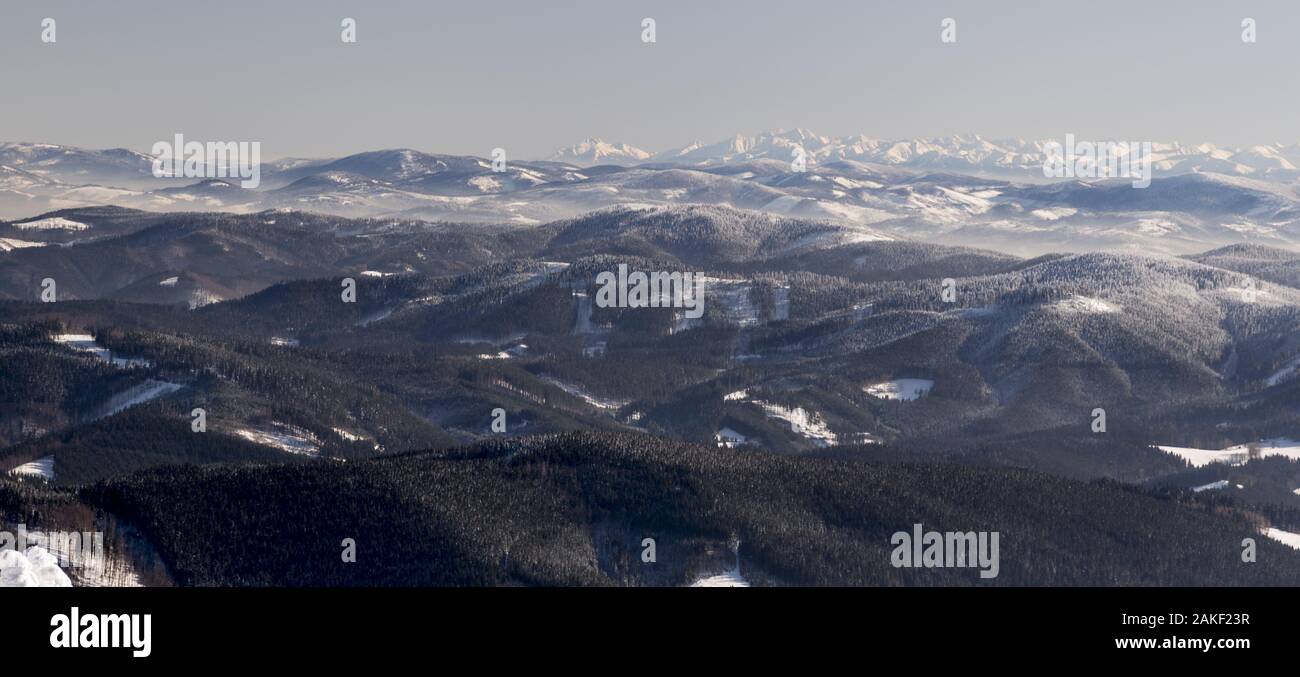 Abbassare colline di Beskids montagne e più Alti Tatra dal Lysa Hora hill in Moravskoslezske Beskydy mountains nella Repubblica Ceca durante freezin Foto Stock