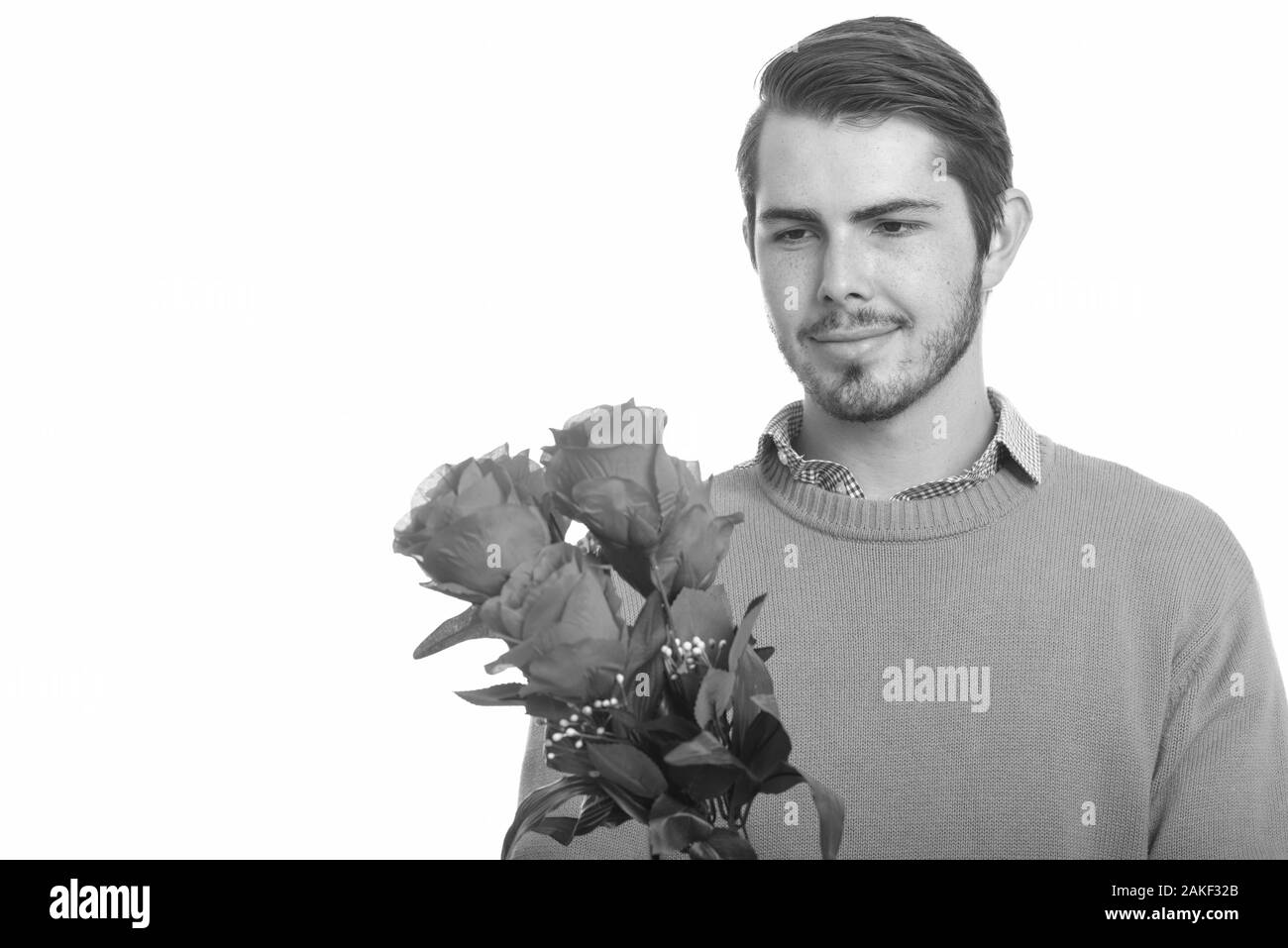 Giovane bel caucasico che tiene rose rosse mentre pensa pronto per San Valentino Foto Stock