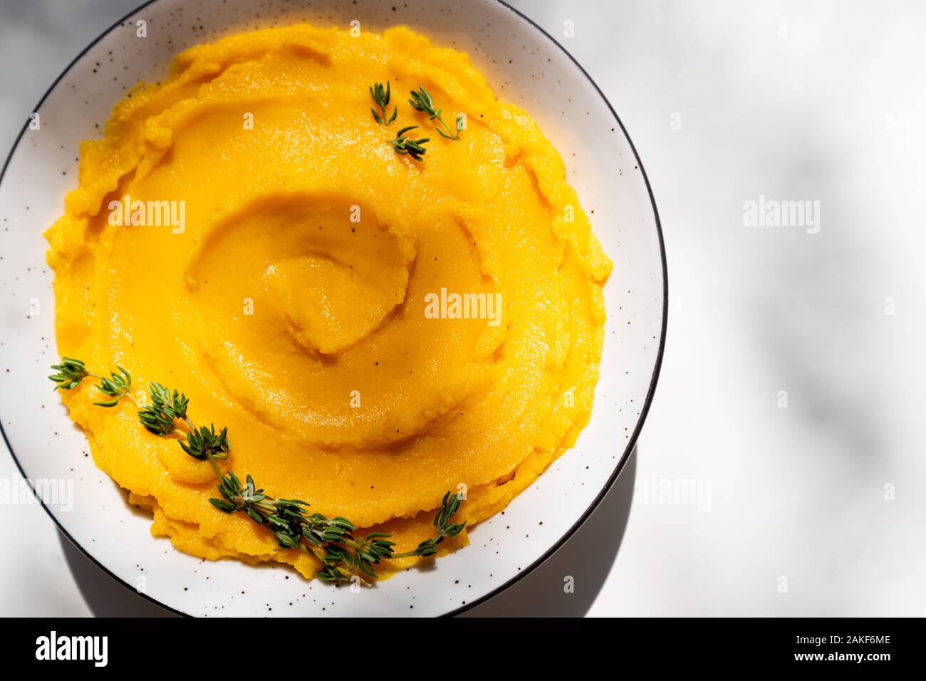 Autunno purea di zucca in una terrina. Autunnale di crema di zucca minestra con timo bianco sul tavolo. Autunno gustoso cibo vegetariano. Vista superiore Foto Stock