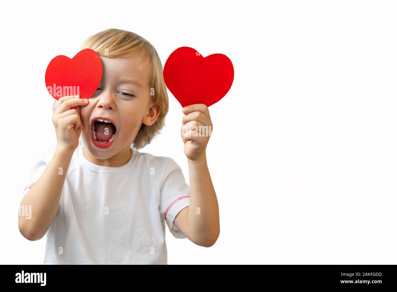 Un ragazzino in una camicia bianca contiene cuori rossi nelle sue mani,  chiude gli occhi e sorrisi su uno sfondo bianco. Il giorno di San  Valentino, Festa della Mamma, International Womens Day