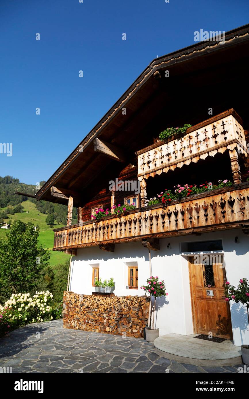 Facciata di un chalet di montagna vicino a Zell am See, Austria. Fiori colorati crescere sul balcone di legno del tradizionalmente concepito edificio. Foto Stock