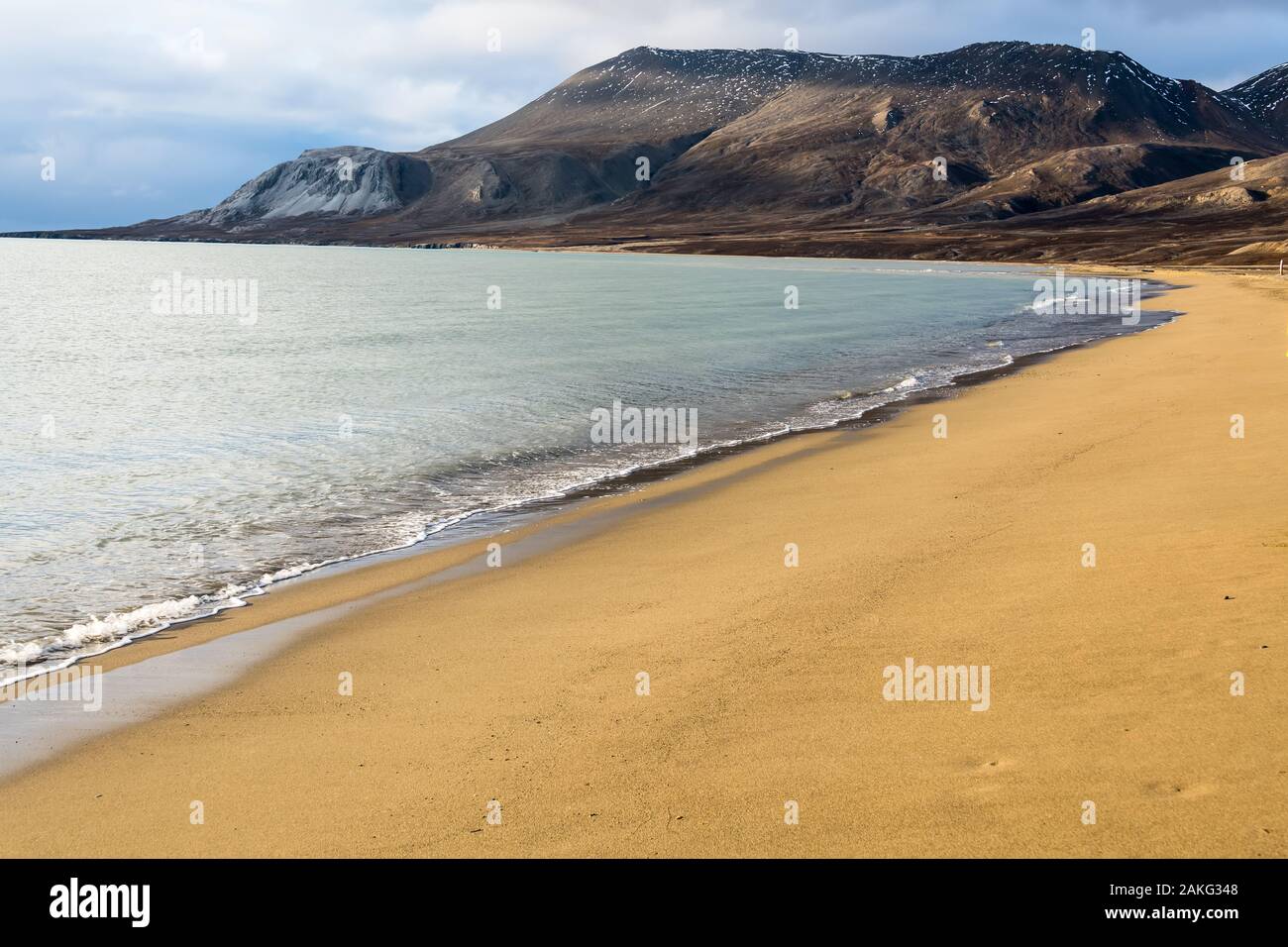 spiaggia di sabbia dorata con picchi oceanici e catena montuosa rocciosa all'orizzonte - splendido paesaggio artico Foto Stock
