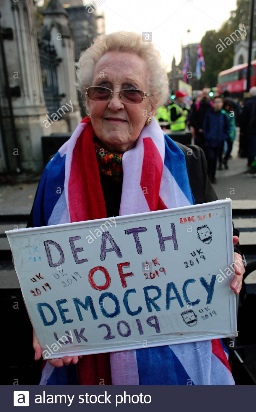 Una donna che tiene una morte alla democrazia segno alle porte del Palazzo di Westminster poco prima di lasciare significa lasciare marzo ci siamo arrivati. Foto Stock