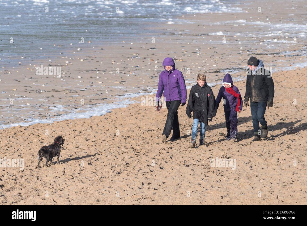 Una famiglia e il loro cane godendo di una passeggiata lungo Fistral Beach in Newquay in Cornovaglia. Foto Stock