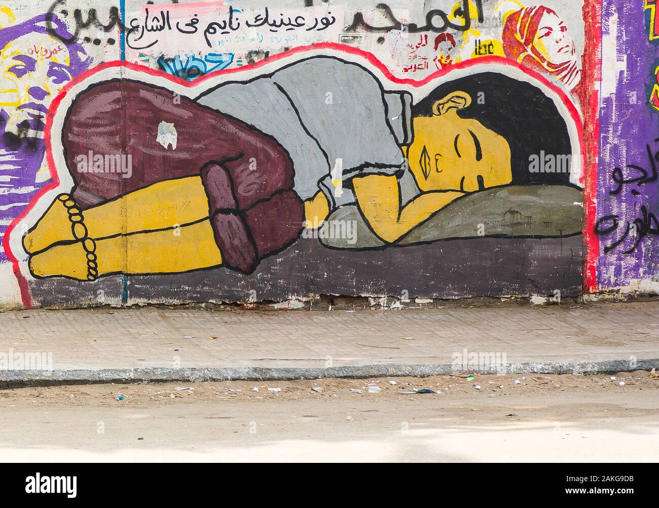 L'Egitto, al Cairo, graffiti della rivoluzione egiziana su Mohamed Mahmoud Street. Un bambino di strada a dormire. Foto Stock