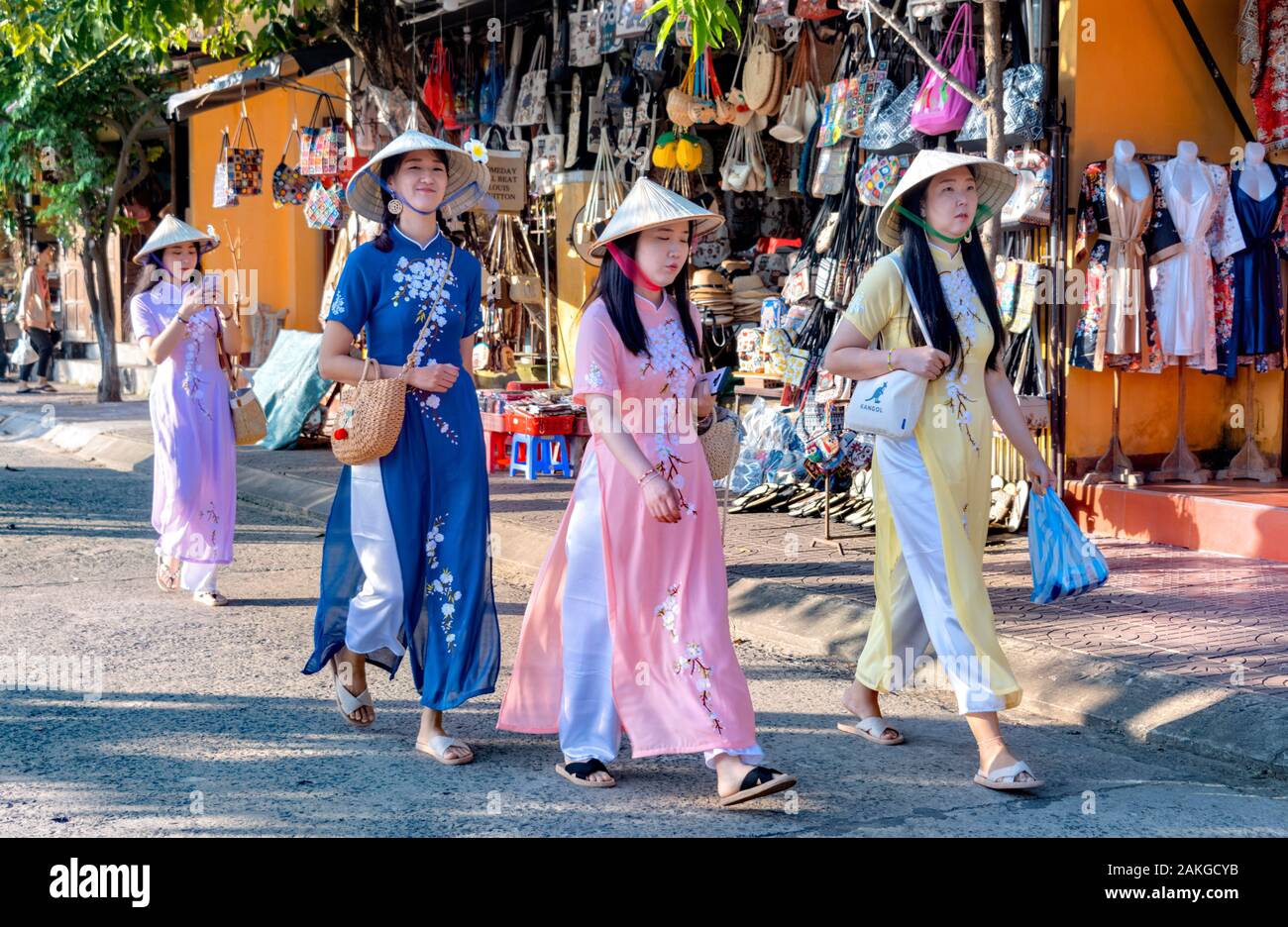 Quattro turisti asiatici donne che indossano cappelli conici, a piedi attraverso il vecchio quartiere Hoi An Vietnam Foto Stock
