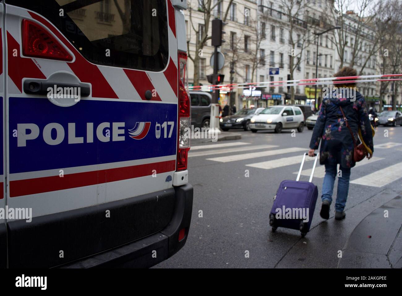 La polizia francese Van e blocco di Cordon road al traffico in previsione delle manifestazioni di protesta del governo le riforme dei sistemi pensionistici, come donna cammina attraverso la barriera con la valigia, viaggi interruzioni durante lo sciopero (la grève), Boulevard Barbès (vicino alla stazione dei treni Gare du nord), 75018, Paris, Francia, 9 gennaio 2020 Foto Stock