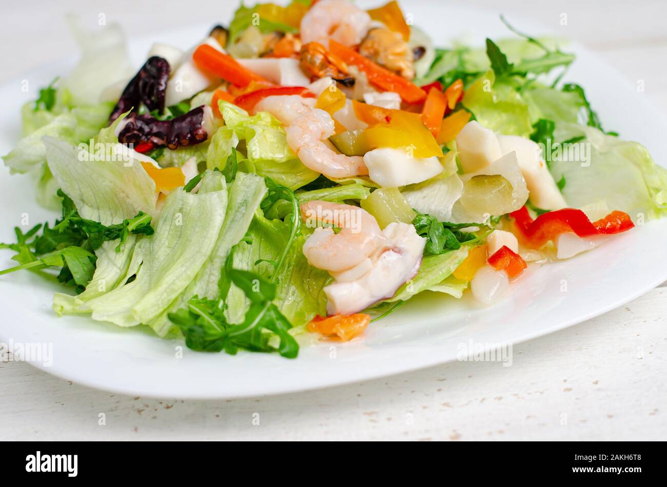 Insalata di pesce con verdure e lattuga su piastra bianca. La delicatezza del Mediterraneo la dieta alimentare. Foto Stock