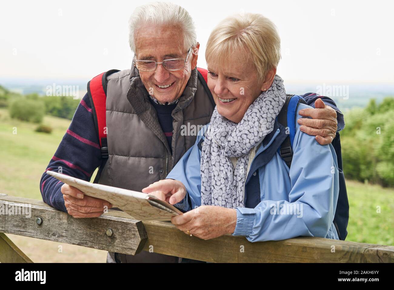 Coppia in pensione in vacanza a piedi in appoggio sul cancello con mappa Foto Stock