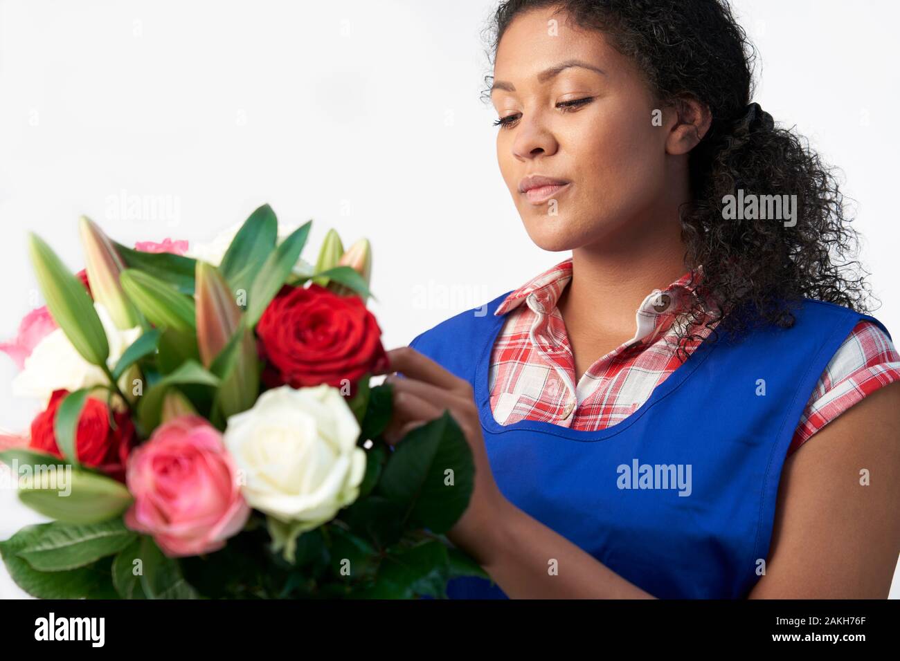 Fiorista Femminile Che Organizza Bouquet Di Lillies E Rose Contro Sfondo Bianco Foto Stock