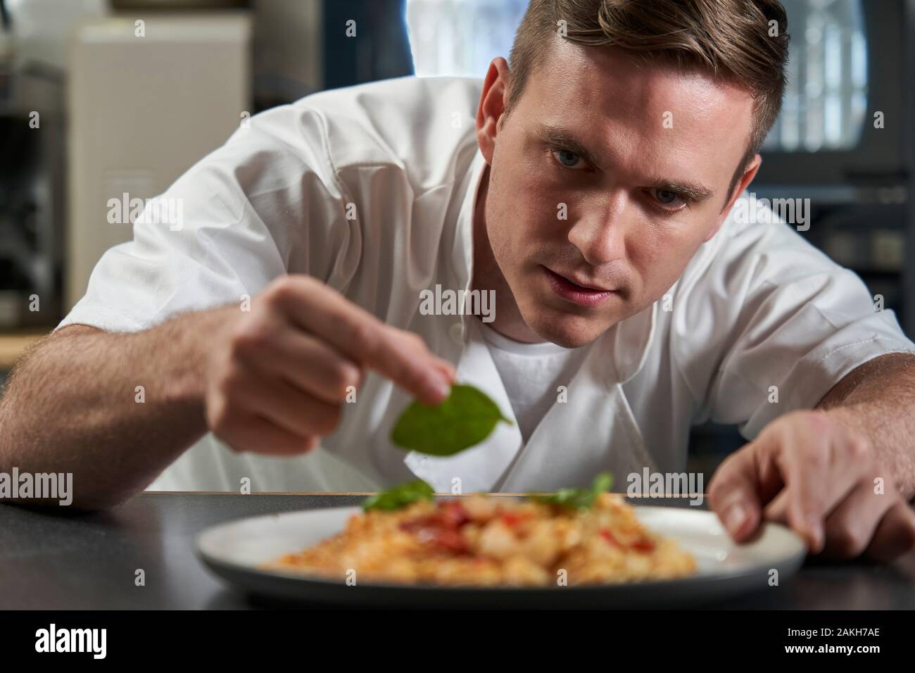 Lo Chef maschio piastra di farcitura di prodotti alimentari in cucina professionale Foto Stock