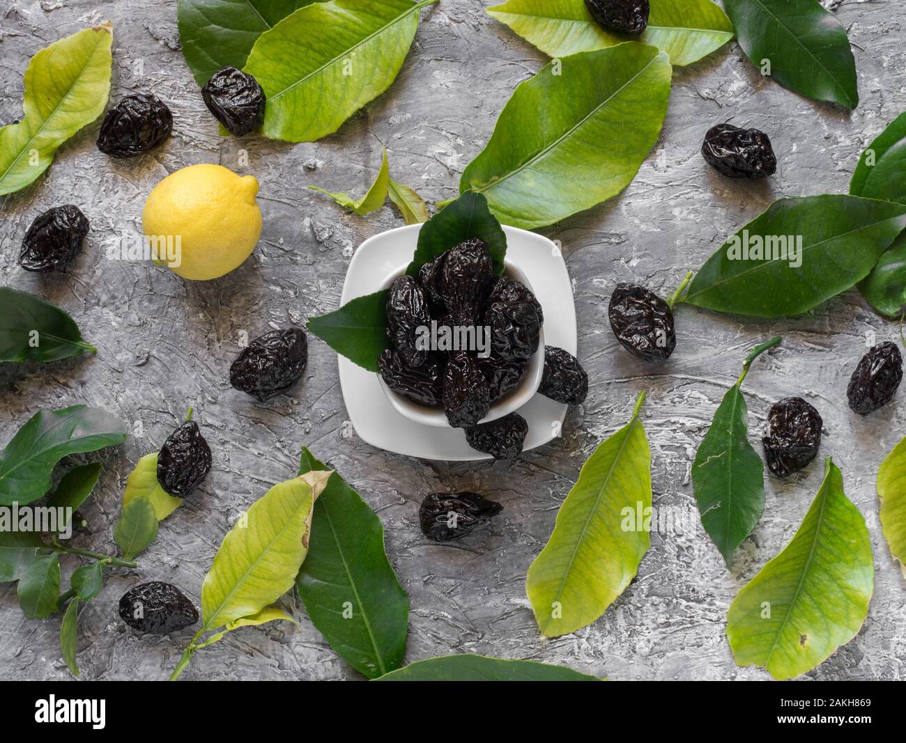 Ciotola di dolce prugne secche con foglie di limone su rustico sfondo in  stucco Foto stock - Alamy