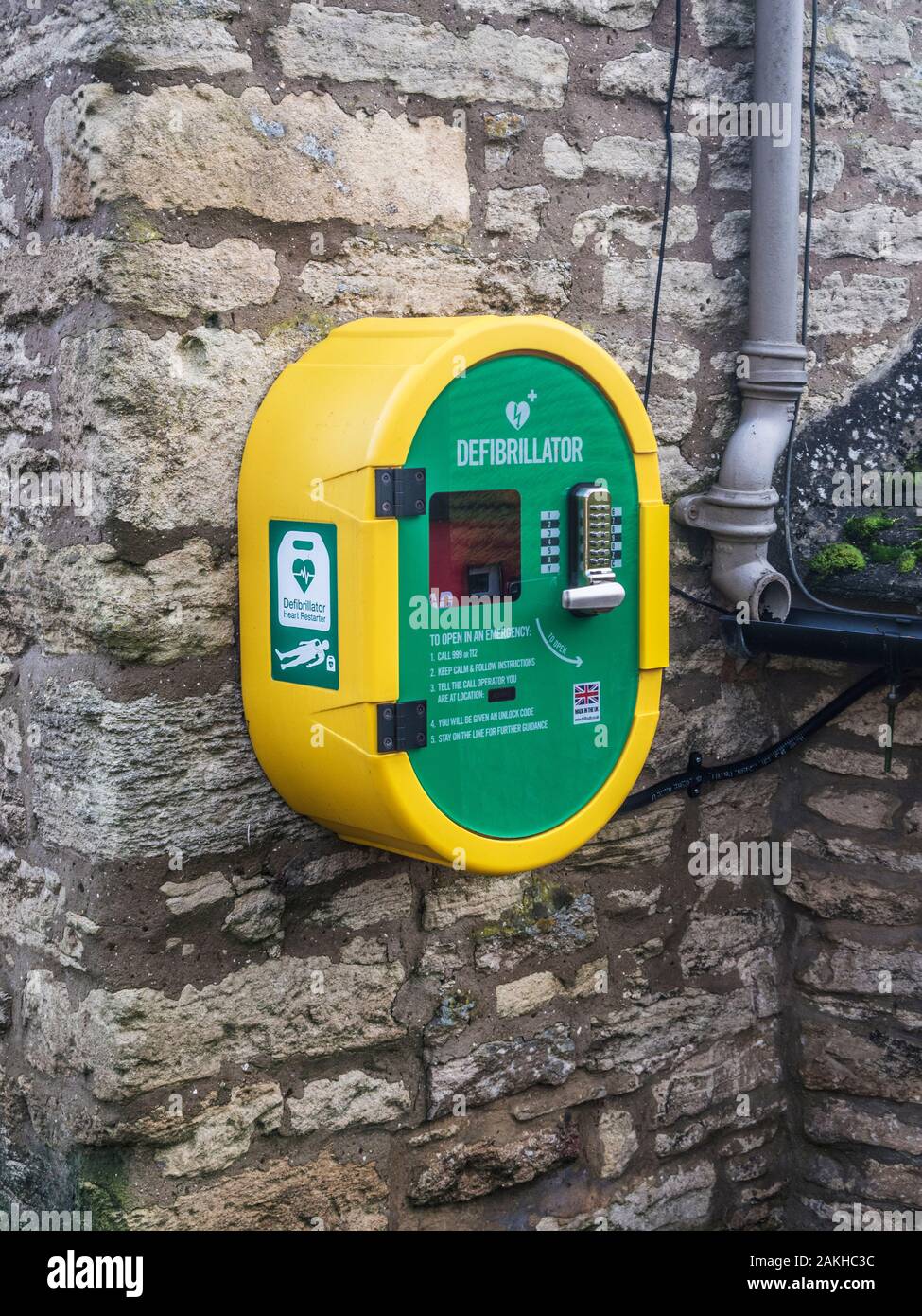 Un moderno pubblico accesso defibrillatore fissato ad una parete di pietra. Foto Stock